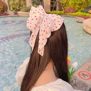 Détail d'une élégante pince à cheveux nœud en mousseline à pois avec des perles