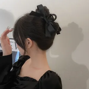 Close-up detail showing an elegant black ribbon bow hair claw clip styled on a classic bun