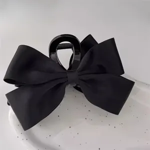Close-up of elegant black ribbon bow claw clip on white ceramic plate
