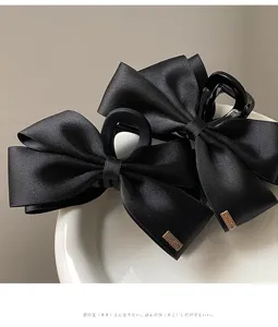 Detail close-up of elegant Hepburn style black satin ribbon bow hair claw clip.