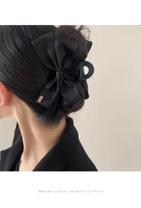 Close-up of a black satin ribbon bow claw clip securing a hair bun in Hepburn style