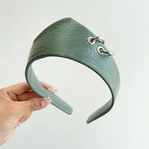 Dettaglio del cerchietto in pelle verde salvia con anelli decorativi in argento metallo