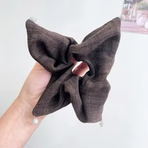 Λεπτομέρεια καφέ υφασμάτινου scrunchie με λαμπερά μενταγιόν από σφαίρες στρας