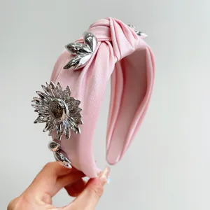 Detailed close-up of a pink knotted wide headband with silver metallic flower decorations