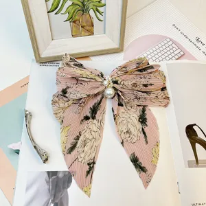 Détail d'une élégante pince à cheveux noeud en mousseline fleurie rose avec perles