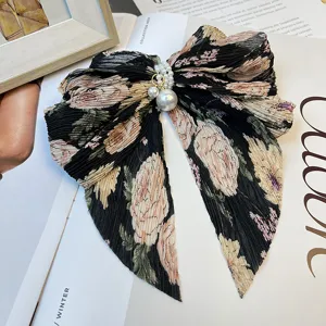 Détail d'une pince à cheveux en mousseline noire à fleurs avec des perles élégantes