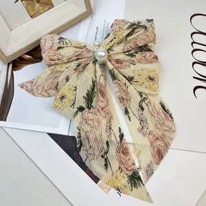 Gros plan d'une pince à cheveux avec nœud en mousseline florale et perles élégantes