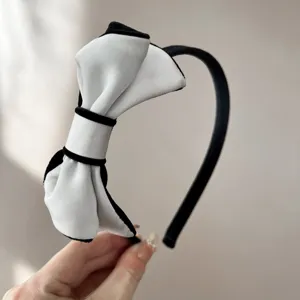 Dettaglio ravvicinato di un elegante cerchietto con fiocco in velluto bianco e nero.