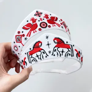 Detailaufnahme eines russischen Folklore-Stirnbands mit roter Stickerei von Vögeln und Pferden