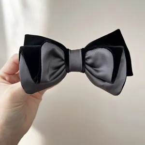 Primo piano di un elegante fermaglio per capelli a fiocco in velluto nero e grigio