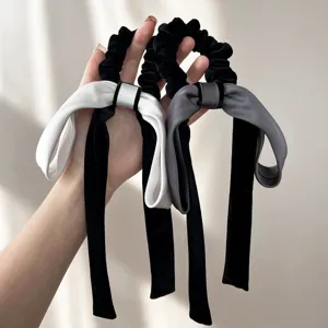 Dettaglio di due eleganti elastici per capelli in velluto con fiocco nero e grigio.