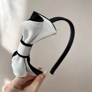 Primo piano di un elegante cerchietto con fiocco in velluto bianco e nero da donna