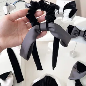 Dettaglio di scrunchie in velluto nero con fiocco grigio, accessorio elegante per capelli