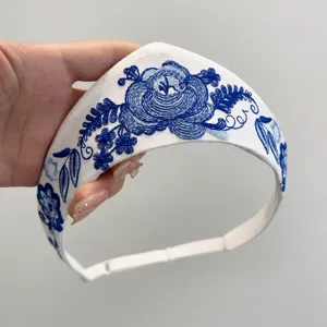 Detailansicht der Stickerei mit blauen Blumenmustern auf einem weißen Retro-Haarband
