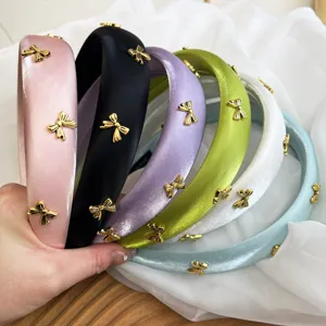 Detailed view of colorful satin padded headbands with gold metal bows