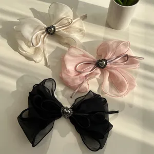 Detalle de pinzas para el cabello con lazo de malla y pedrería de corazón en tres colores