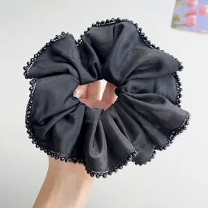 Close-up of a black satin scrunchie with delicate crystal bead edging detail
