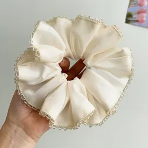 Close-up of cream satin scrunchie with delicate crystal bead trim detail