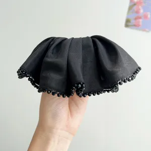 Detail view of black satin scrunchie featuring elegant crystal beaded edges for hair styling