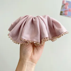 Detail view of pink satin scrunchie featuring elegant crystal beaded trim for hair