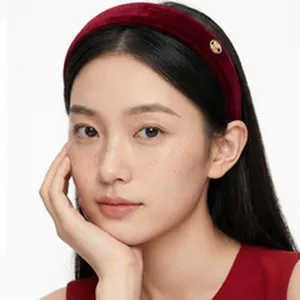 Detailed view of an elegant padded dark red velvet headband worn by a female model.