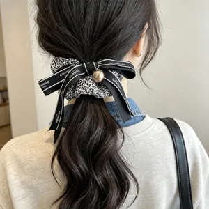 Detalle de un coletero con estampado de leopardo, perla y lazo negro decorativo.