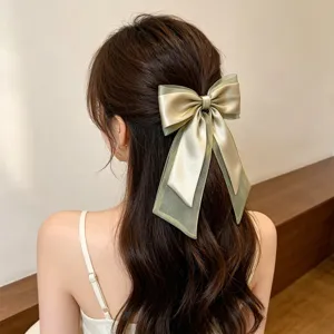 Elegant light green organza bow hair clip with long streamers on a woman's wavy hair