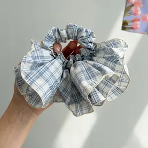 Close-up of oversized blue plaid scrunchie with ruffled edges and soft fabric texture
