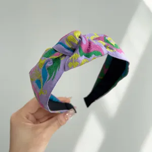 Primer plano de una diadema con nudo violeta bohemia y bordado floral vibrante