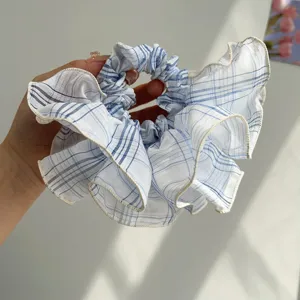 Close-up detail of a blue and white checkered ruffled scrunchie hair tie for daily hair styling