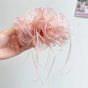 Close-up detail of an elegant pink organza banana hair clip with long flowing ribbons.