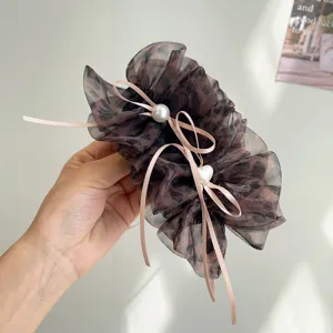 Gros plan détaillé d'une pince banane en tulle léopard avec perles et rubans roses