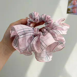 Detailed view of a large pink plaid scrunchie with ruffled skirt design for hair