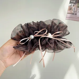 Détail d'une pince à cheveux léopard en mesh avec d'élégants rubans roses à nœuds