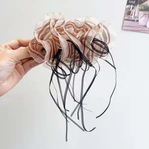 Close-up detail of elegant striped organza hair clip with flowing black ribbons