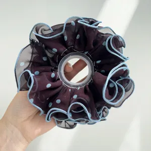 Vue détaillée de la texture en maille à pois sur un chouchou marron à volants froncés.