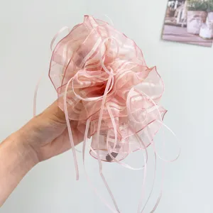 Close-up of pink striped organza hair clip with elegant ribbons and ruffles