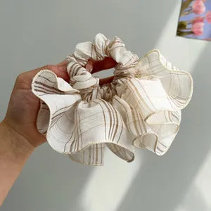 Close-up of a Korean-style oversized ruffled scrunchie with a brown plaid pattern