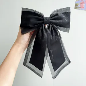Close-up detail of a large black organza bow hair clip with elegant sheer ribbons
