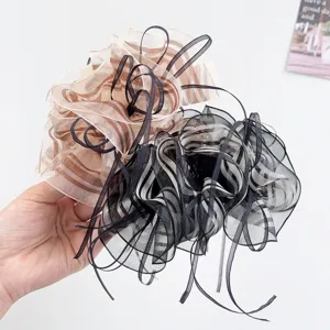 Detailed view of two elegant ruffled organza hair claw clips in beige and black.