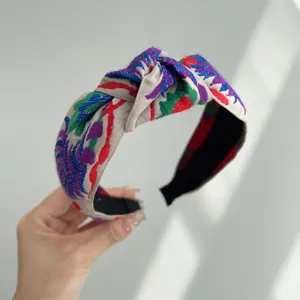 Detalle de una diadema bohemia retro con nudo y bordados étnicos muy coloridos.