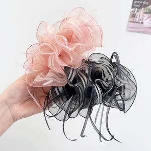 Detailed view of elegant pink and black chiffon bow hair clips held in hand for scale