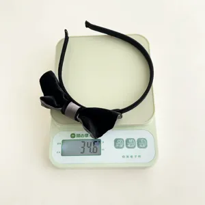 Vista dettagliata che mostra il peso di 34,6g di un cerchietto con fiocco in velluto nero