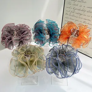 Close-up of five elegant ruffled mesh bow hair claw clips displayed on acrylic stands