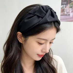 Detalle de una diadema ancha de tela negra con nudo llevada por una modelo asiática