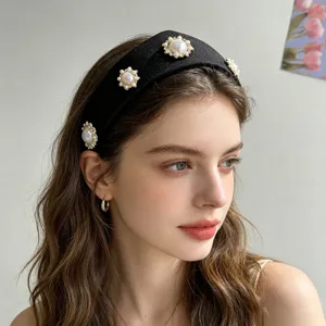 Nahaufnahme eines schwarzen Vintage-Haarreifs mit eleganten Perlenblumen-Verzierungen.