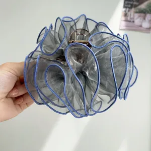 Close-up view of elegant grey ruffled mesh hair claw clip for fashionable updos and styling