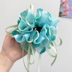 Close-up of a forest-style teal floral scrunchie with pale green ribbons