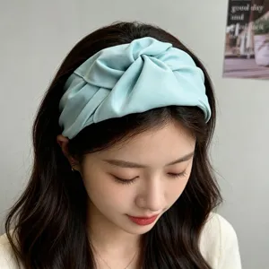 Detalle de una elegante diadema de tela anudada en azul claro lucida por una modelo