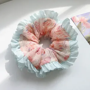 Close-up detail of a pastel mesh scrunchie with light blue ruffles and floral print